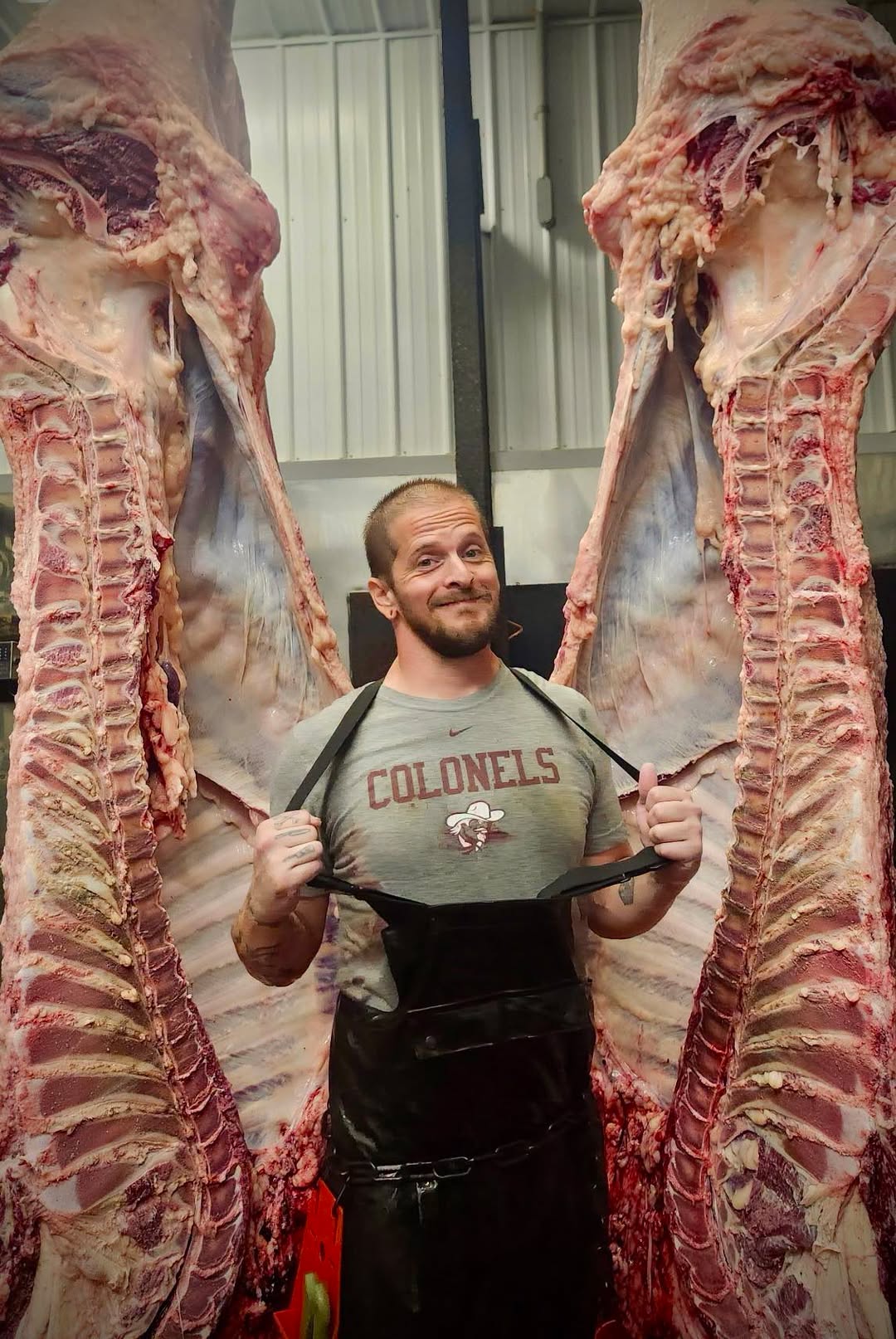 A butcher standing between two sides of beef in the processing area